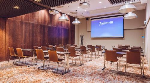 a conference room with tables and chairs and a screen at Radisson Blu Seaside Hotel, Helsinki in Helsinki