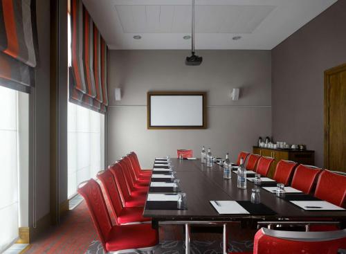 a conference room with a long table and red chairs at Radisson Blu Hotel, Durham in Durham