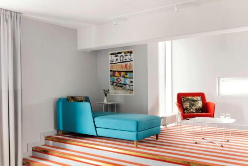 a living room with a blue chair and a red chair at Radisson Blu Seaside Hotel, Helsinki in Helsinki