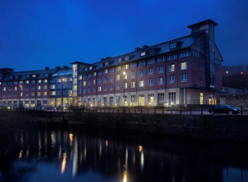 a large brick building next to a river at night at Radisson Blu Hotel, Durham in Durham