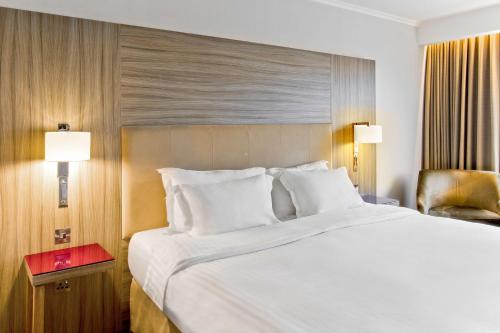 a bedroom with a large white bed and a chair at Radisson Blu Manchester Airport in Hale