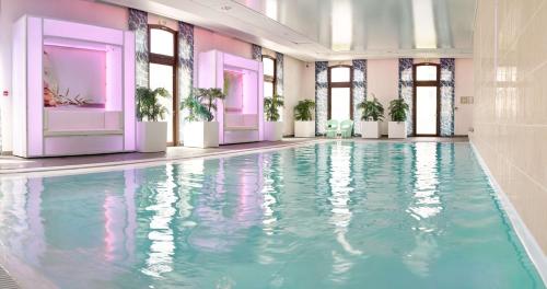 a swimming pool with blue water in a room with windows at Radisson Blu Hotel Paris, Marne-la-Vallée in Magny-le-Hongre