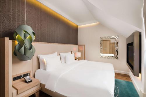 a bedroom with a large white bed and a tv at Radisson Blu Béke Hotel, Budapest in Budapest
