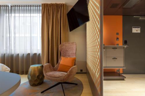 a bedroom with a chair with an orange pillow on it at Radisson Blu Hotel, Lucerne in Luzern