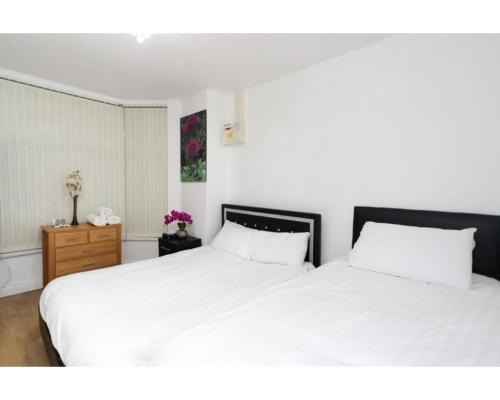 a bedroom with two white beds and a dresser at Balmain Apartments in Leeds