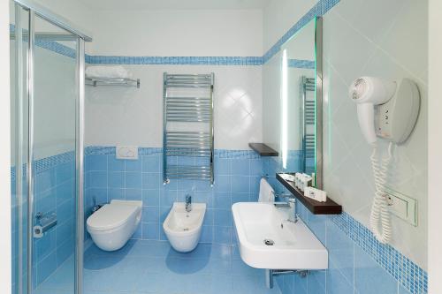 bagno piastrellato blu con servizi igienici e lavandino di Hotel Lido ad Alba Adriatica