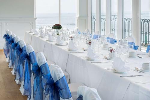 a long table with white tables and blue chairs at Park Inn by Radisson Palace in Southend-on-Sea
