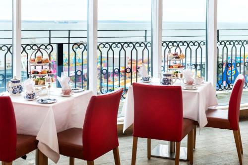 a dining room with a table and chairs with a view of the ocean at Park Inn by Radisson Palace in Southend-on-Sea