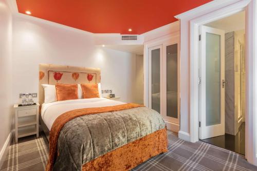 um quarto com uma cama grande e um tecto laranja em Radisson Blu Sussex Hotel, London em Londres