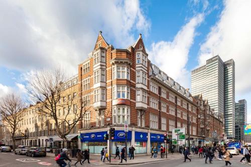 un grupo de personas cruzando una calle frente a un edificio en Radisson Blu Edwardian Grafton Hotel, London, en Londres