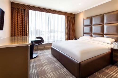 a hotel room with a bed and a desk at Radisson Blu Edwardian Heathrow Hotel, London in Hillingdon