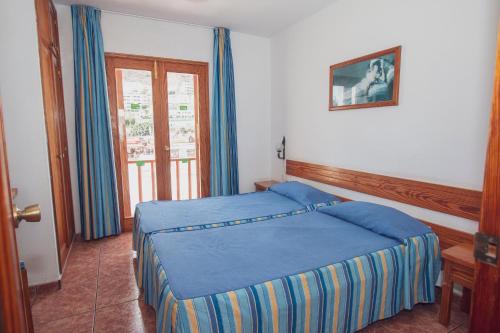 a bedroom with a blue bed and a window at Montecarlo Apartamento30 in Puerto Rico de Gran Canaria