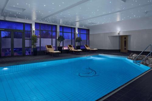 a large swimming pool in a hotel room with chairs at Radisson BLU Hotel and Spa, Limerick in Limerick