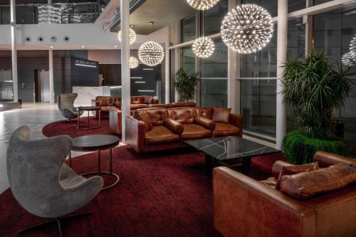 a lobby with leather couches and tables and chairs at Radisson Blu Hotel London Stansted Airport in Stansted Mountfitchet