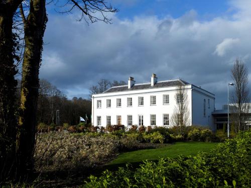 a white house with a garden in front of it at Radisson BLU Hotel & Spa, Little Island Cork in Cork