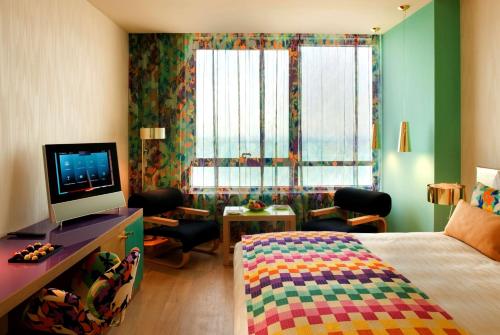 a bedroom with a bed and a desk with a television at Symphony Style Hotel Kuwait in Kuwait