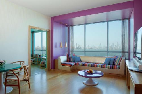 a living room with a couch and a large window at Symphony Style Hotel Kuwait in Kuwait