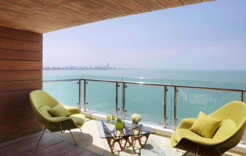 a balcony with two chairs and a glass table at Symphony Style Hotel Kuwait in Kuwait