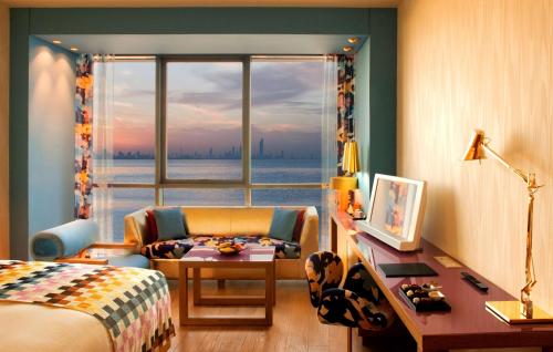 a bedroom with a bed and a desk and a window at Symphony Style Hotel Kuwait in Kuwait