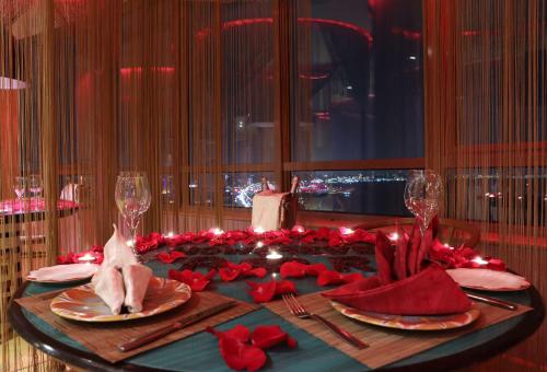 a dining table with red roses and napkins on it at Symphony Style Hotel Kuwait in Kuwait