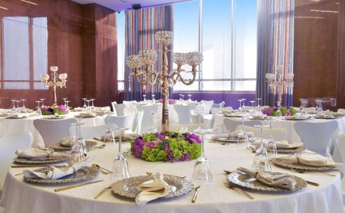 a dining room with white tables and white chairs at Symphony Style Hotel Kuwait in Kuwait