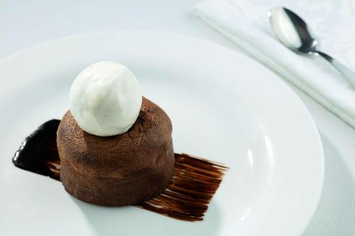 a chocolate dessert with ice cream on a white plate at Symphony Style Hotel Kuwait in Kuwait