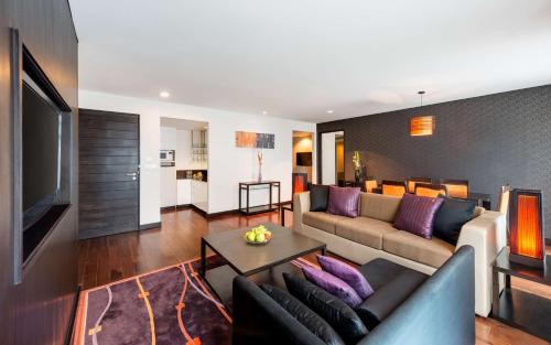 a living room with a couch and a tv at Radisson Suites Bangkok Sukhumvit in Bangkok