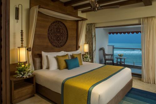 een slaapkamer met een bed en uitzicht op de oceaan bij Radisson Blu Resort Temple Bay Mamallapuram in Mahabalipuram