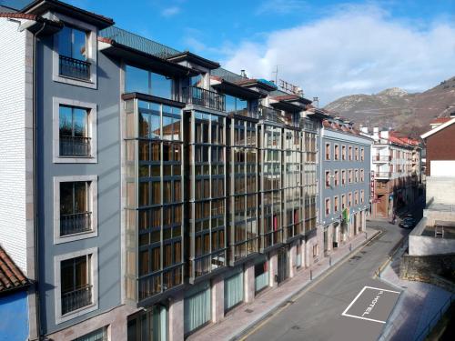 an apartment building on a street with mountains in the background at Hotel Cangas de Onis Center in Cangas de Onís