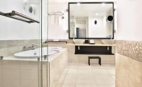 a bathroom with two sinks and a tub and a mirror at Radisson Blu Resort Fiji in Denarau