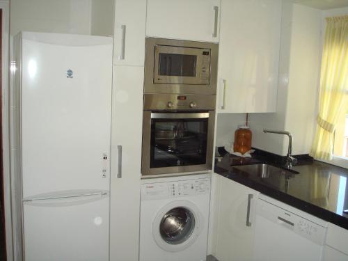 una cocina con lavadora y microondas en Apartamentos Valles, en Broto