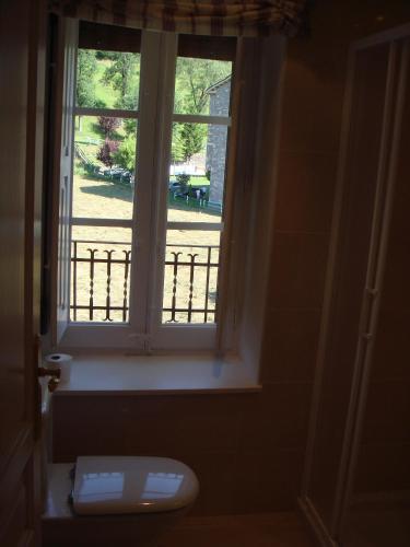 a window in a bathroom with a toilet in front of it at Apartamentos Valles in Broto