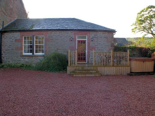a small brick house with a wooden gate and stairs at Auchendennan Farm Self Catering Cottages in Balloch
