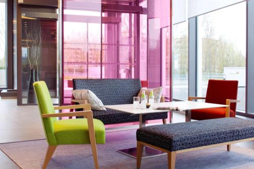 Cette chambre comprend une table, des chaises, une table et des chaises. dans l'établissement Park Inn by Radisson Lille Grand Stade, à Villeneuve d'Ascq