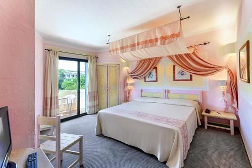 a bedroom with a large bed and a balcony at Grand Hotel Smeraldo Beach in Baja Sardinia