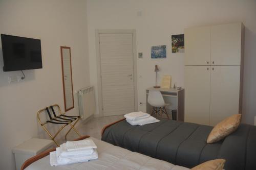 Habitación con 2 camas, escritorio y TV. en ART B&B, en Caltanissetta