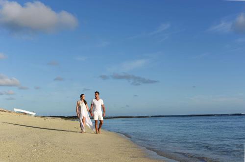 two people walking on the beach with their surfboards at Radisson Blu Poste Lafayette Resort & Spa (Adults Only) in Poste Lafayette
