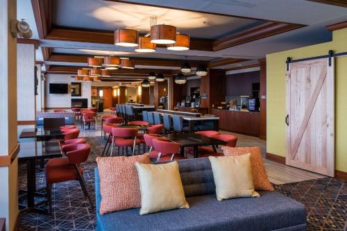 a lobby with a couch and tables and chairs at Wyndham Moline on John Deere Commons in Moline