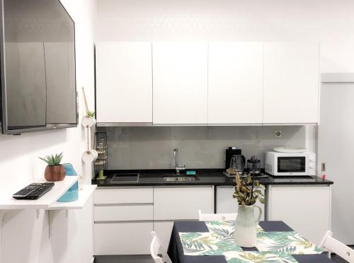 a white kitchen with white cabinets and a table at Sea, Sand and Sun Spot - Espinho Beach in Espinho