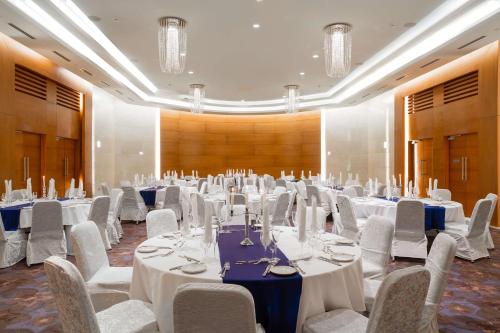 um grande salão de banquetes com mesas e cadeiras brancas em Radisson Blu M'Bamou Palace Hotel, Brazzaville em Brazavile
