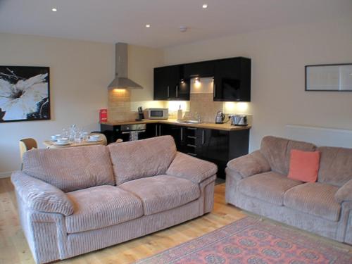 a living room with two couches and a kitchen at Auchendennan Farm Self Catering Cottages in Balloch
