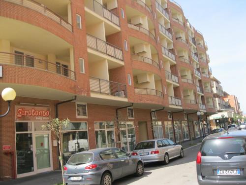 a red brick building with cars parked in front of it at Residence Mediterraneo in Marina di Grosseto