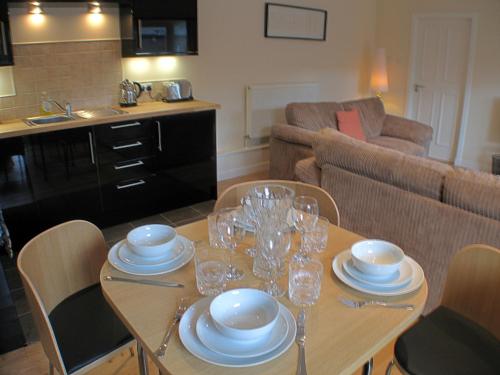 a table with plates and glasses on it in a living room at Auchendennan Farm Self Catering Cottages in Balloch