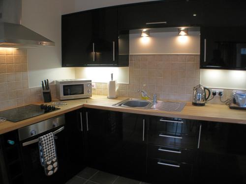 a kitchen with a sink and a microwave at Auchendennan Farm Self Catering Cottages in Balloch