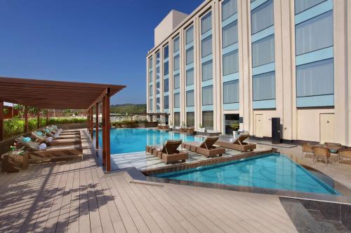 a hotel patio with a pool and chairs and a building at Radisson Blu Jammu in Jammu