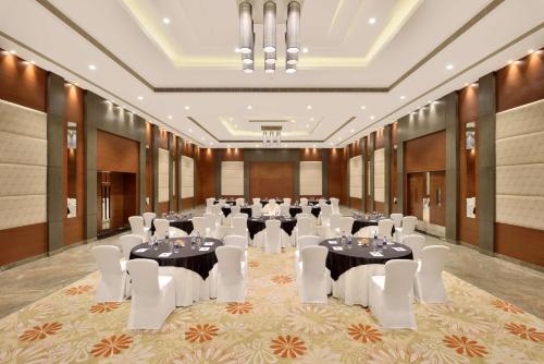 a banquet hall with tables and white chairs at Radisson Blu Pune Hinjawadi in Pune