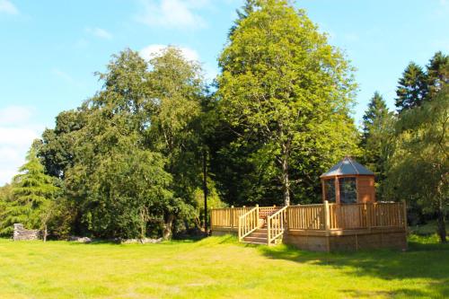 a wooden gazebo in a field with trees at Auchendennan Farm Self Catering Cottages in Balloch