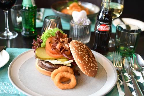 a sandwich on a plate with onion rings on a table at Park Inn By Radisson Hasselt in Hasselt