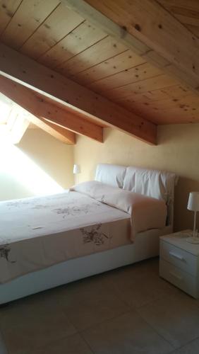 a bedroom with a white bed with a wooden ceiling at Casa da Brunetto in Costarainera