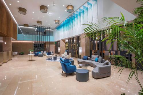 a lobby with blue chairs and couches and plants at Radisson Blu Hotel, Larnaca in Larnaca